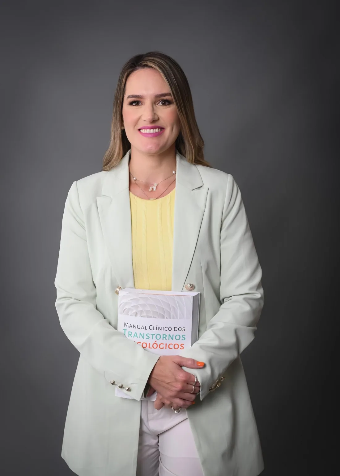 Natália Gontijo segurando um manual clínico de transtornos psicológicos
